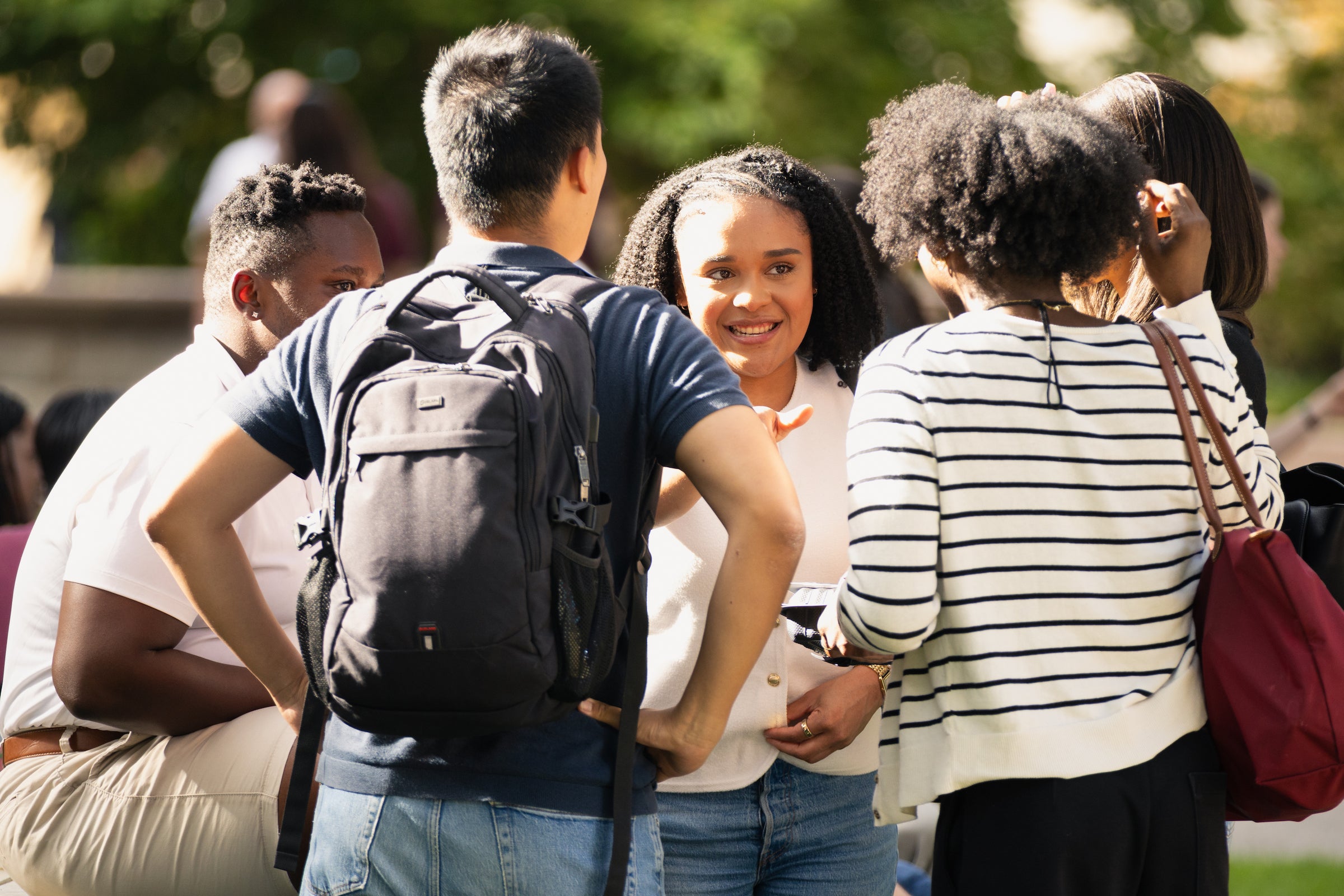 A group of students engage in conversation at an outdoor event.