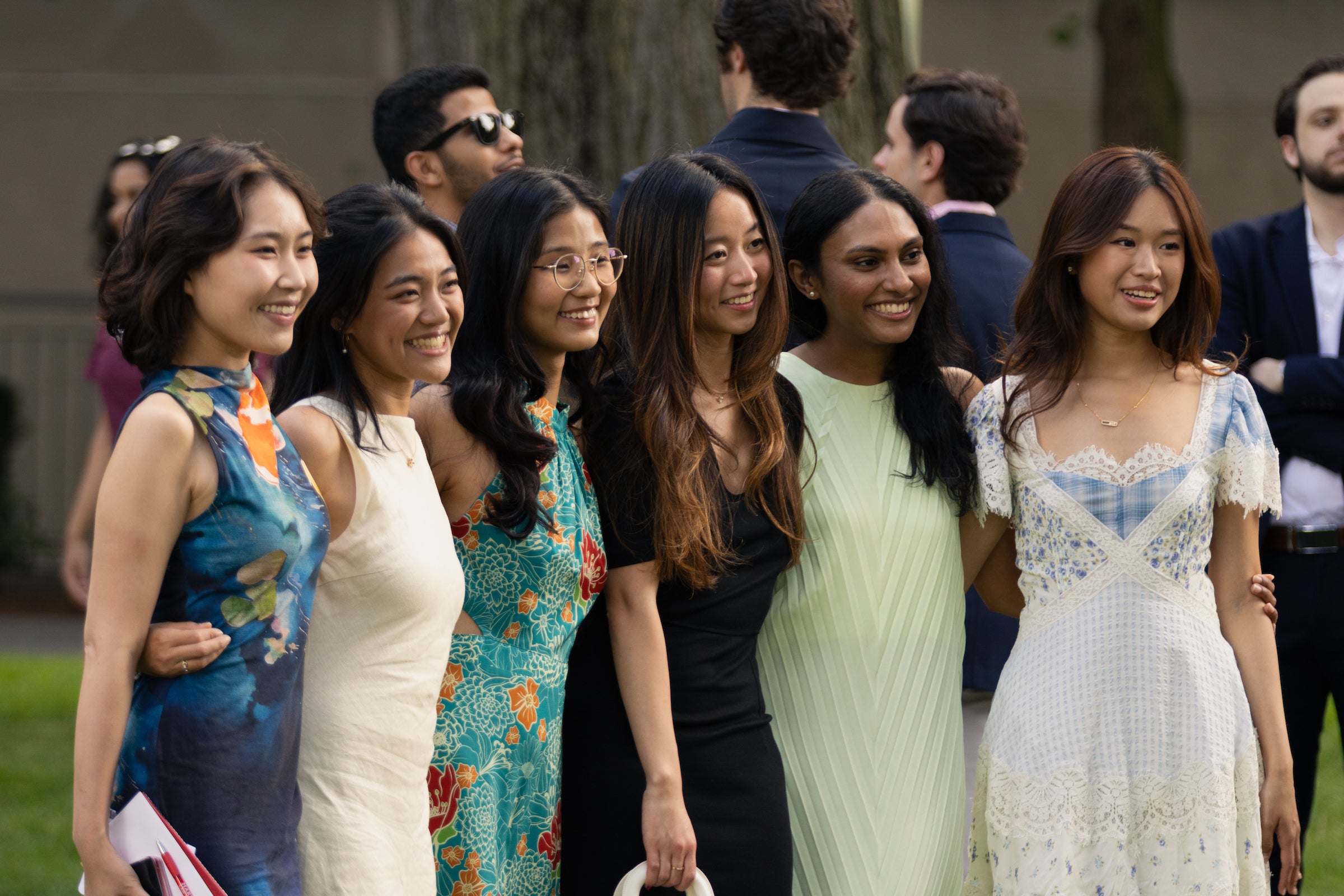 A group of six students smile for a photo, dressed in elegant, colorful attire.