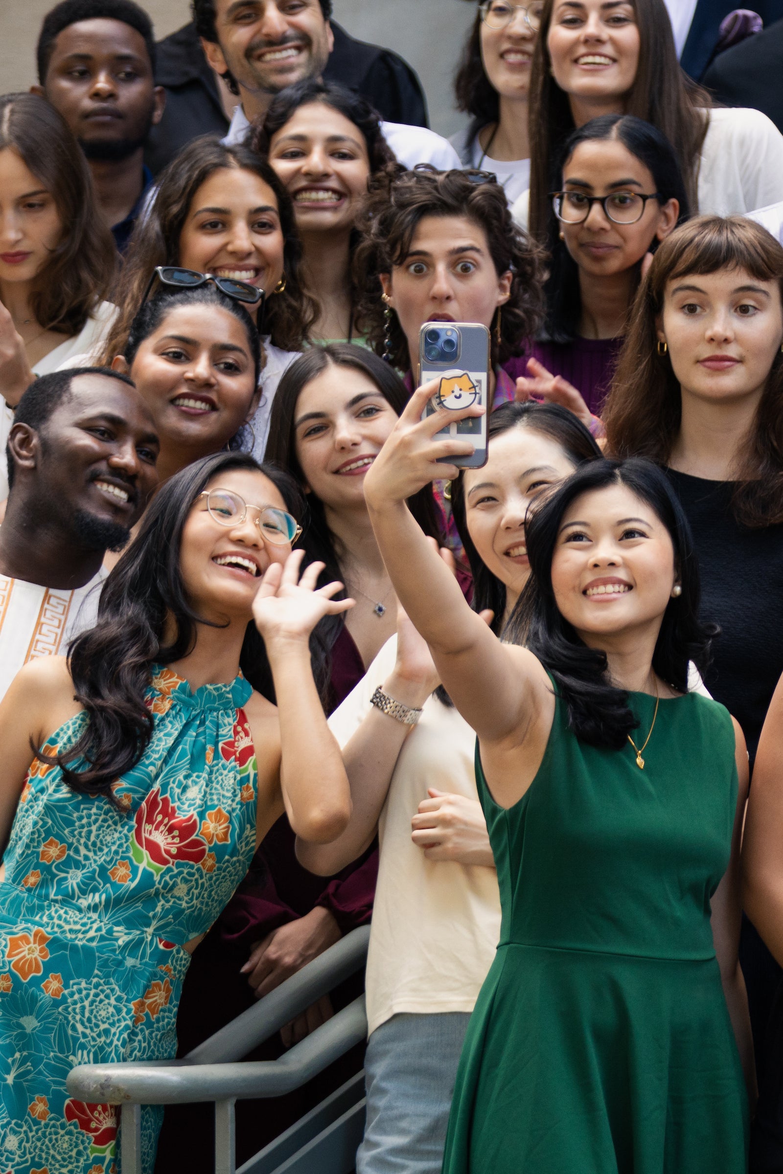 A group of students take a selfie while waiting to take part in a large group photo.