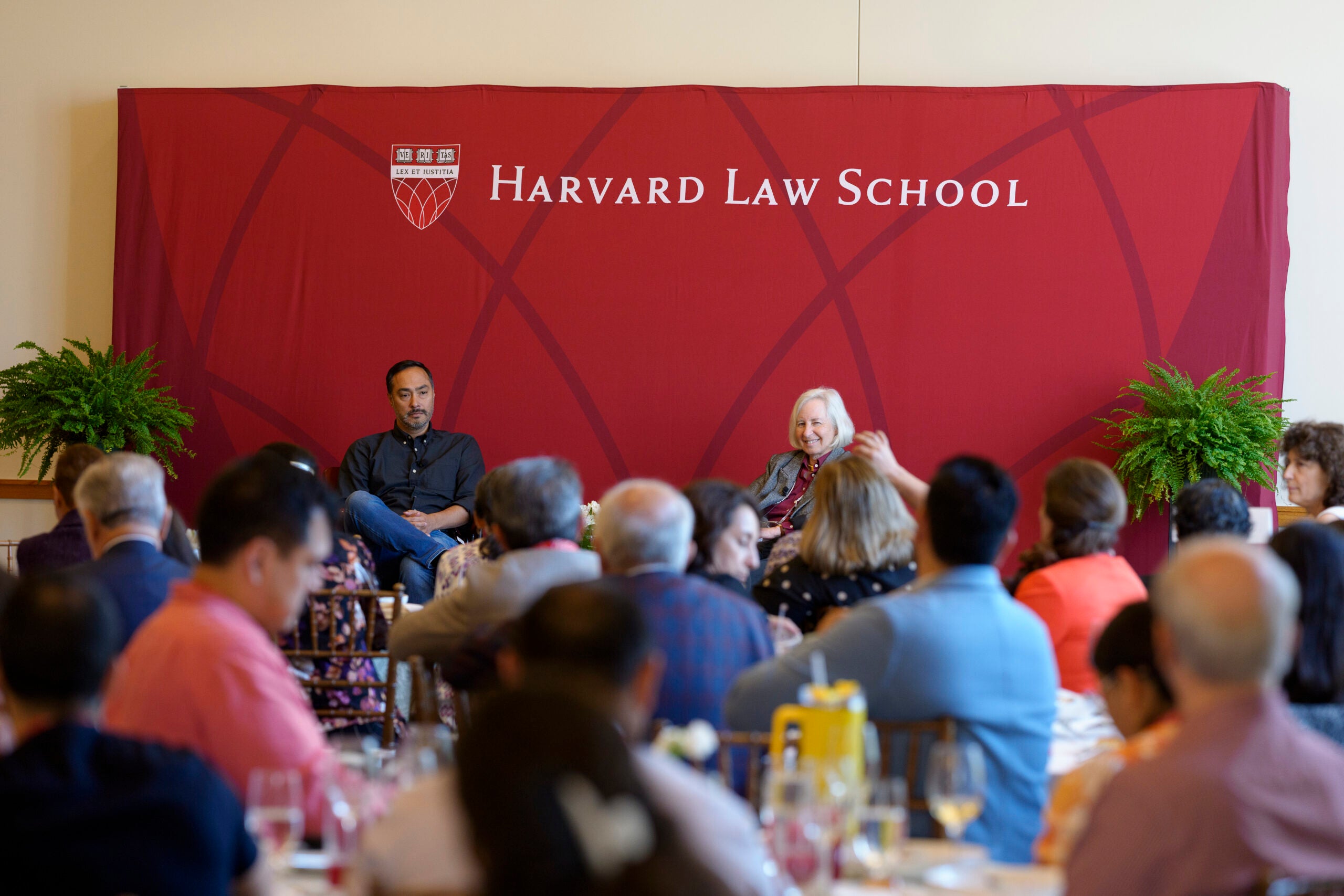 Joaquin Castro ’00 and Martha Minow on stage speaking to an audience of seated alumni.