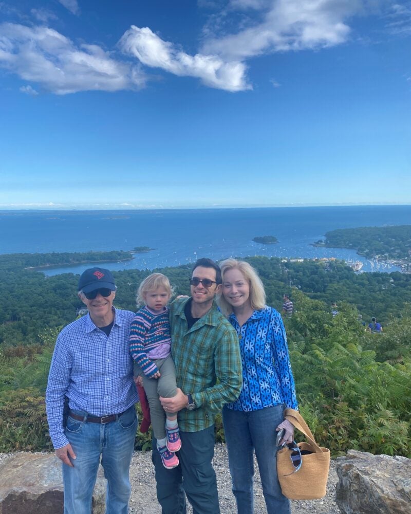 Dennis Langer M.D., J.D. ’83 and Susan Langer, M.D. with their family on top of a mountain smiling.