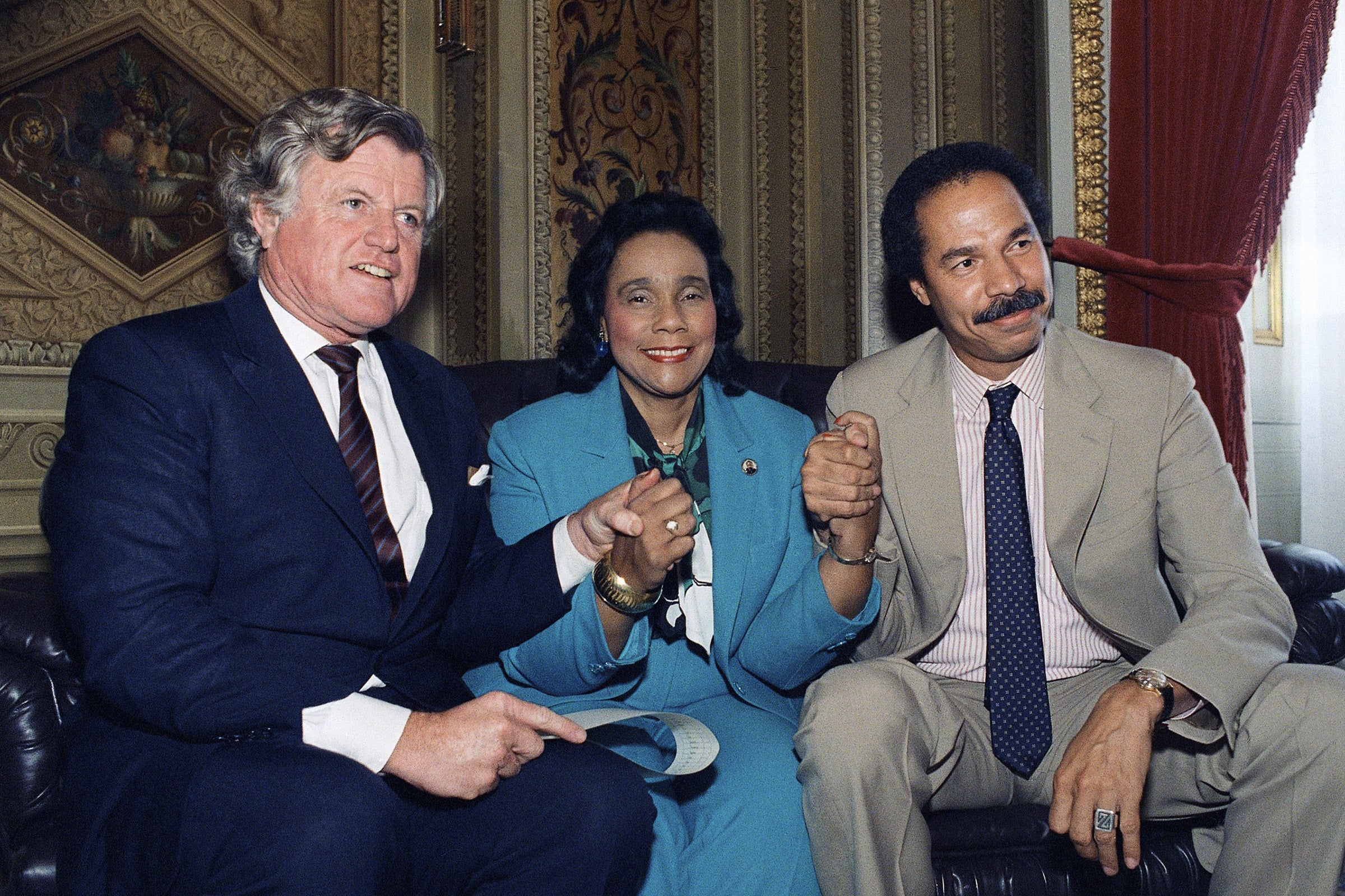 Senator Edward Kennedy, Coretta Scott King, and Randall Robinson hold hands.