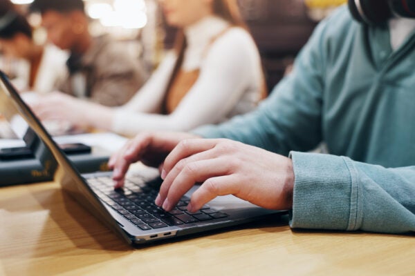 a student in class typing on a laptop.