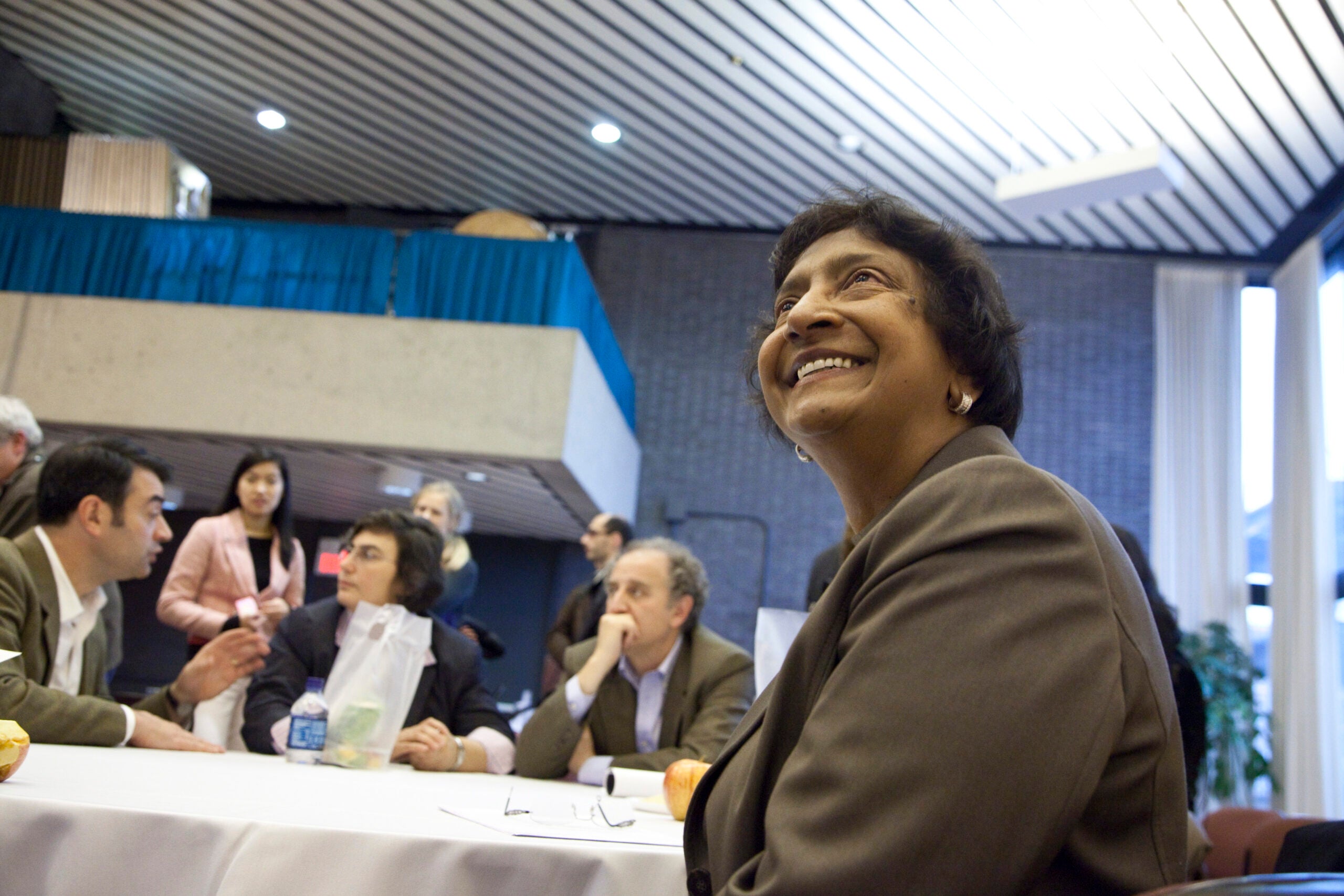 Navi Pillay smiles while sitting at a table at an event.