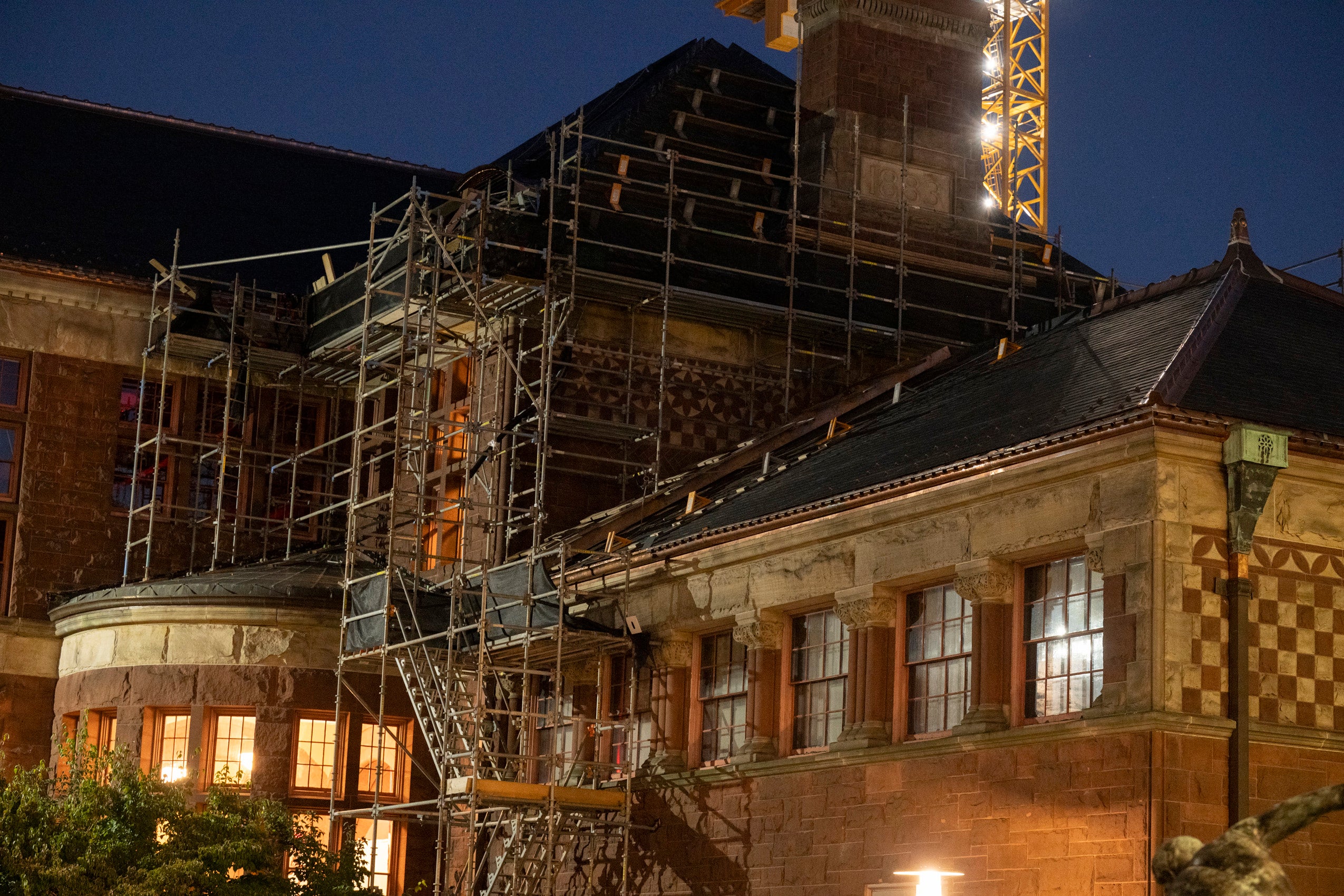 Detail of building at dusk showing scaffolding on the exterior as it is being renovated.