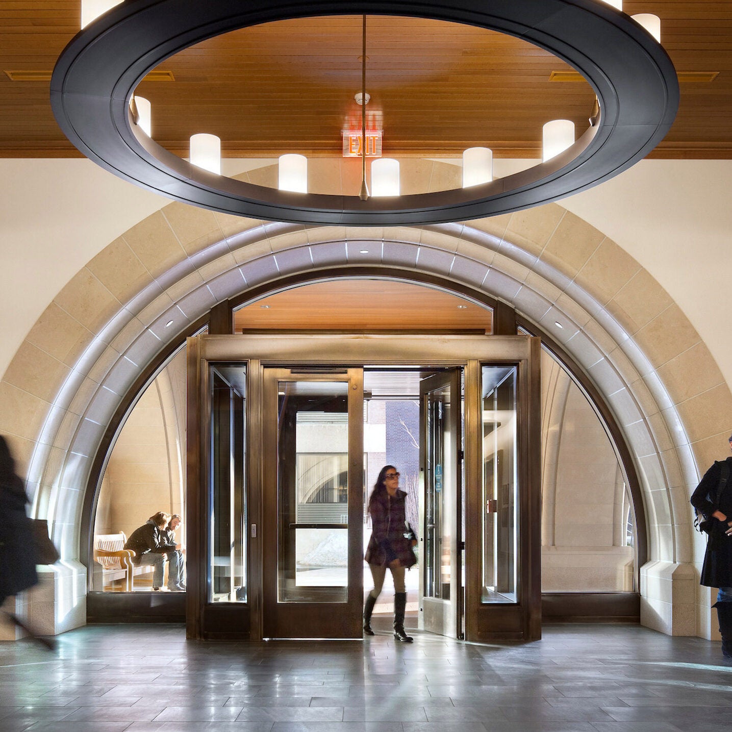 Interior shot of the entranceway to the Wasserstein building. Students entering the doorway and talking in the lobby.