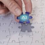 Blank white puzzle with one piece missing w/ a hand hovering over with the missing piece which is blue and says AI