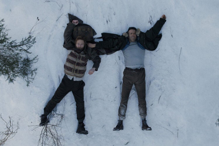 Two men laying on snow.