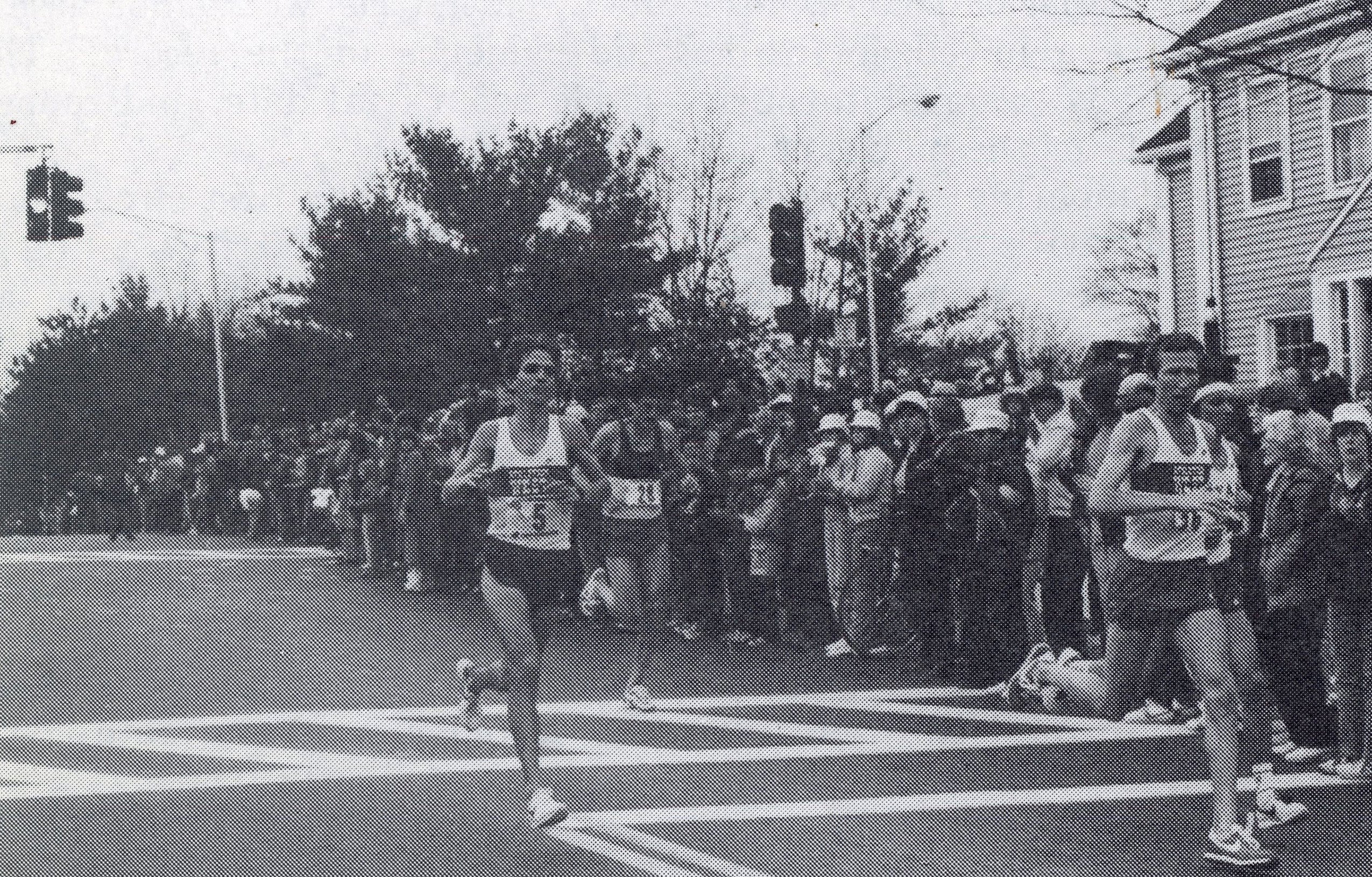 News photo of crowds looking on as runners race by.