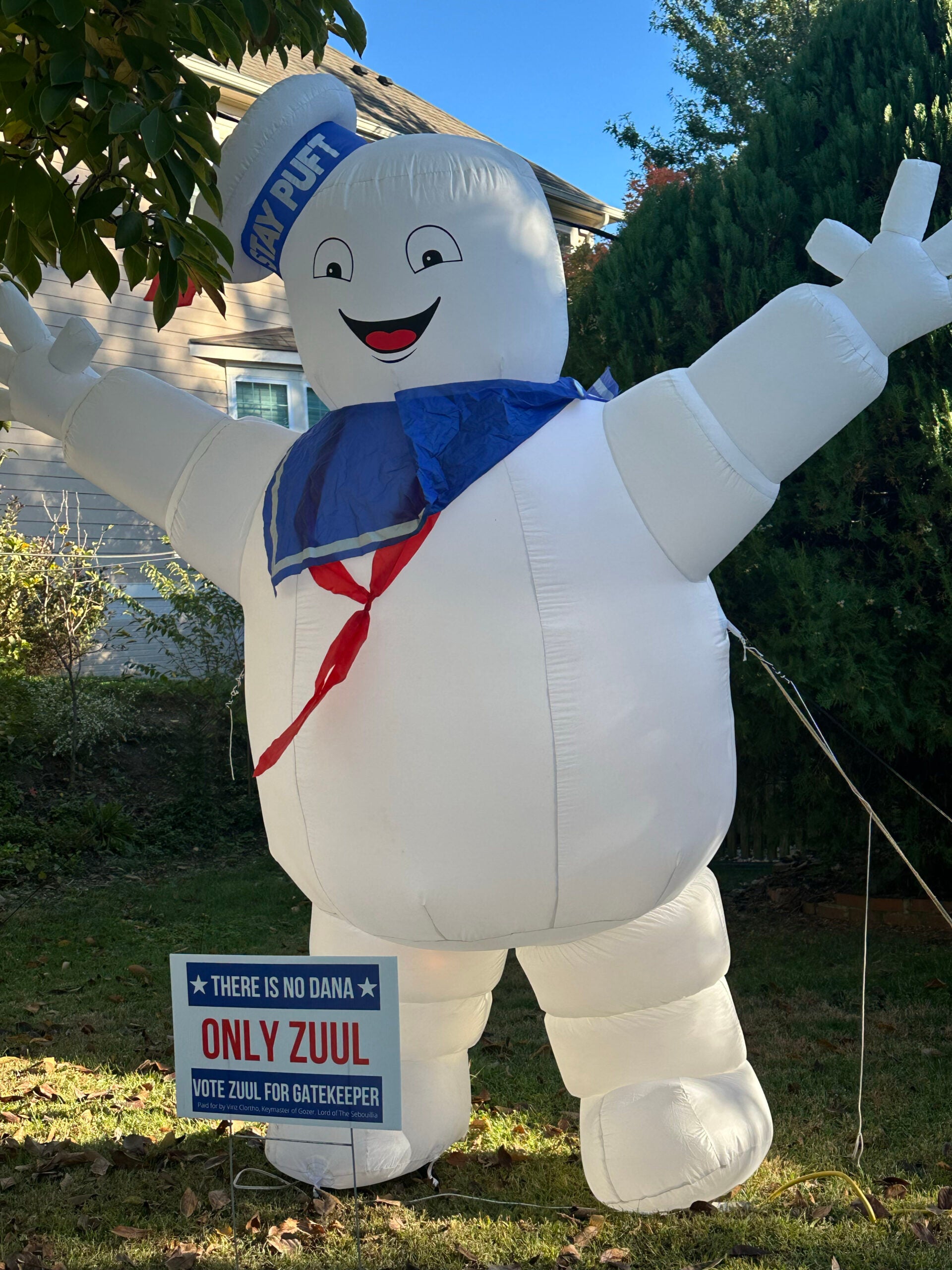 A giant Stay Puft Marshmallow Man inflatable stands behind a sign endorsing Zuul, a candidate running for the fictional office of interdimensional Gatekeeper.