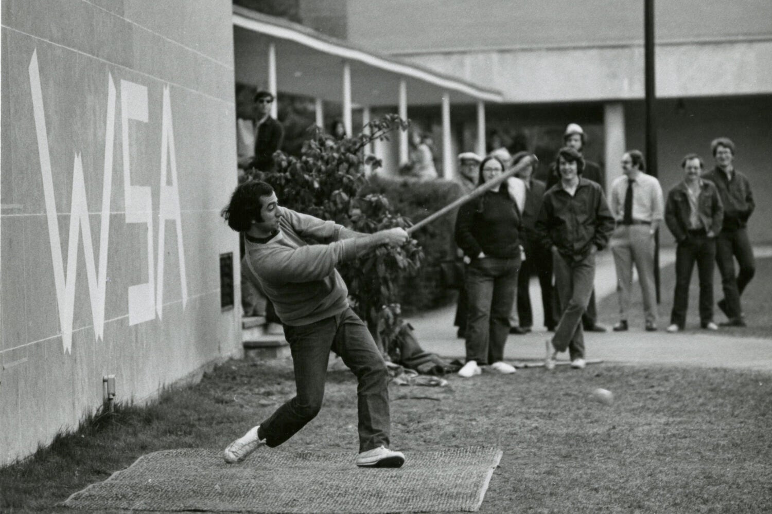 Man hits a ball with a makeshift bat.