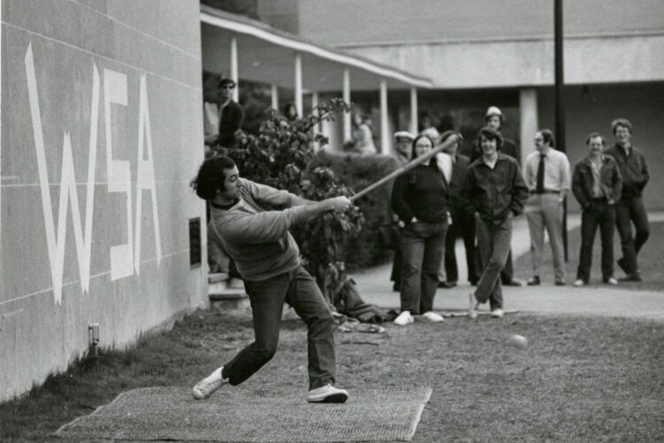 Man hits a ball with a makeshift bat.