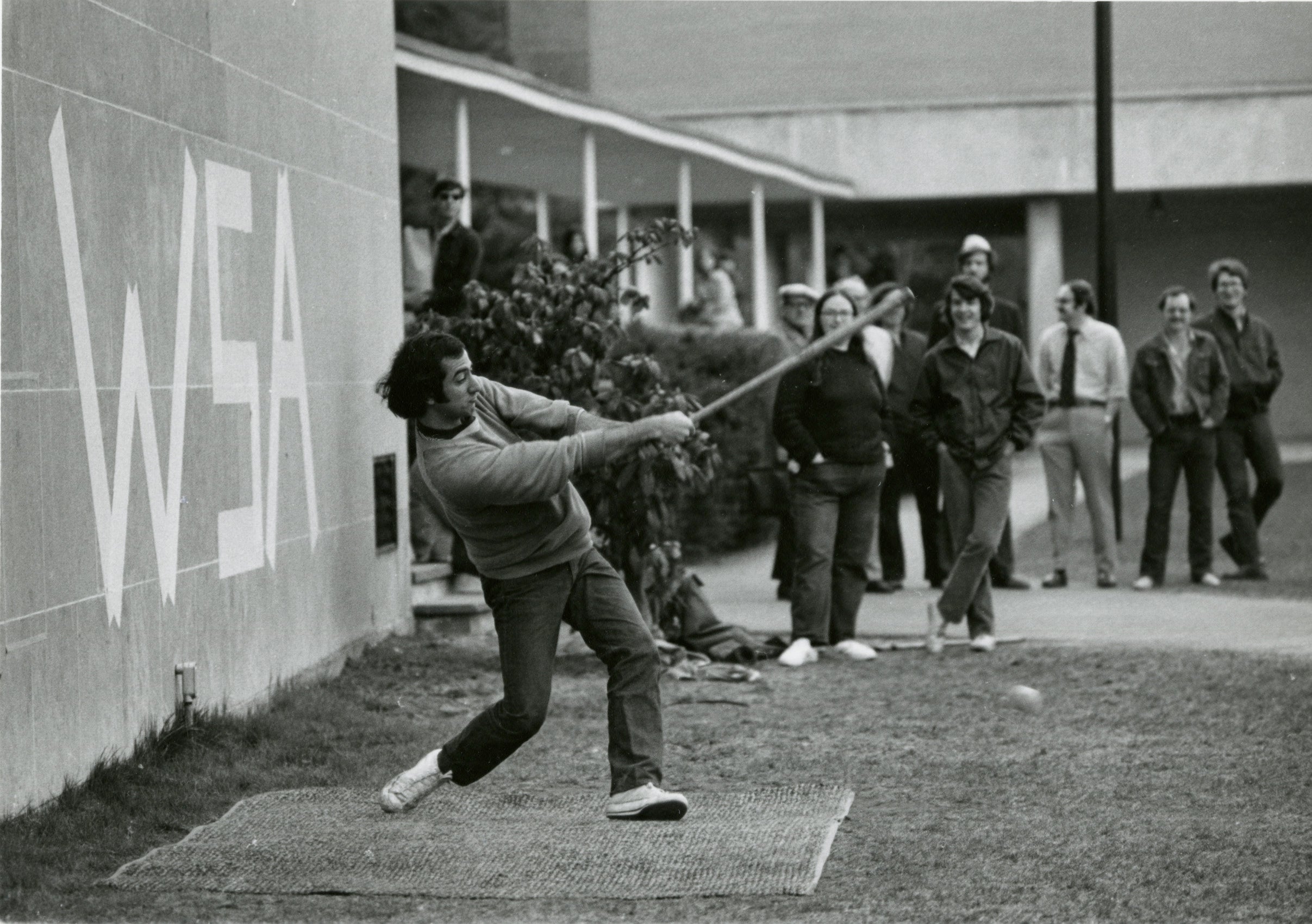 Man hits a ball with a makeshift bat.