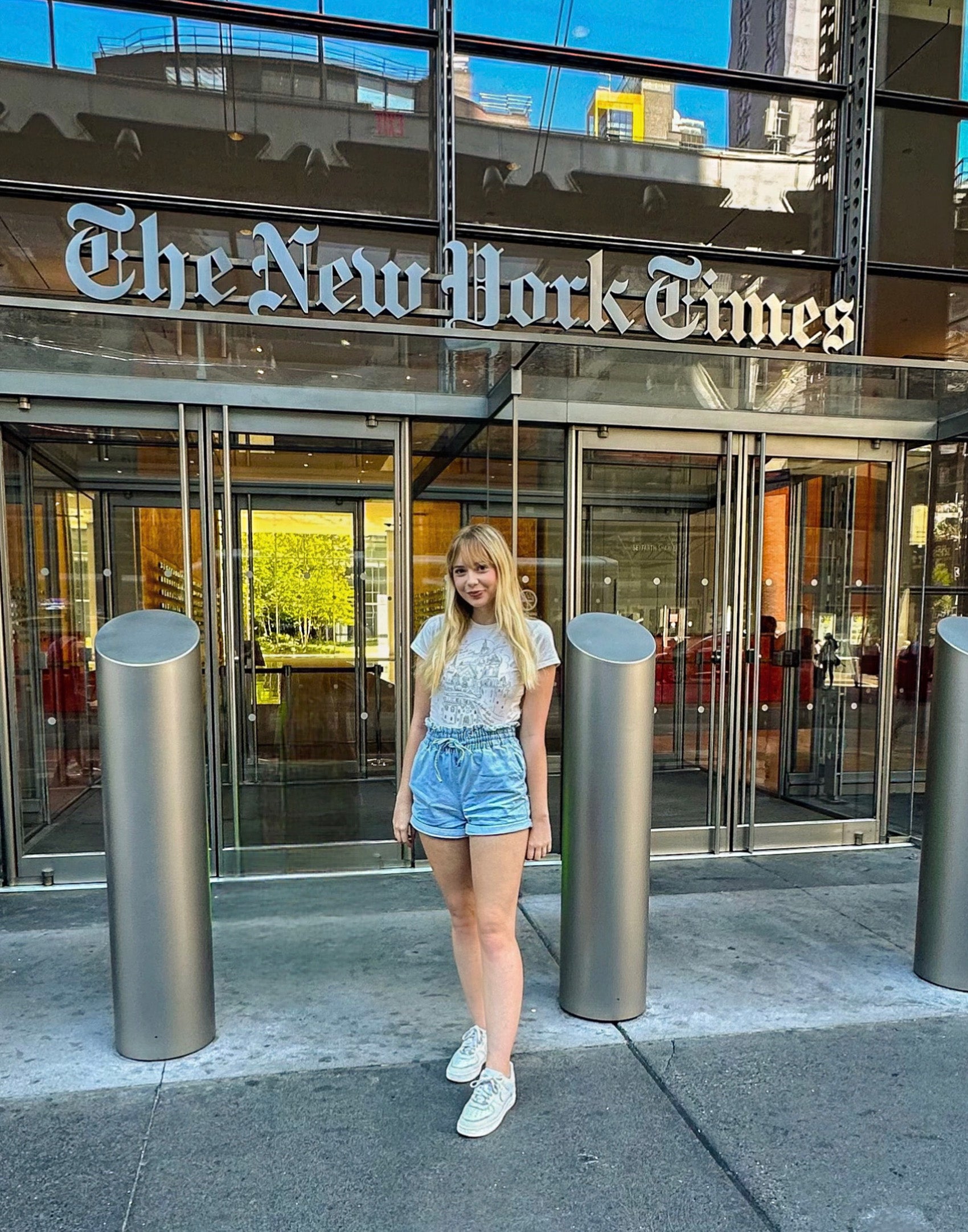 A woman stands in front of the entrance to the New York Times building.